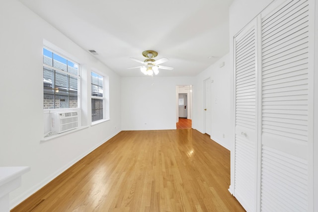 unfurnished bedroom featuring cooling unit, light hardwood / wood-style floors, a closet, and ceiling fan