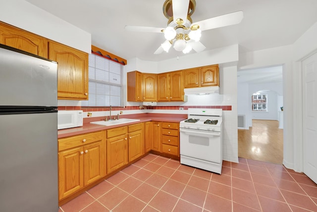 kitchen with tile patterned floors, sink, tasteful backsplash, ceiling fan, and white appliances