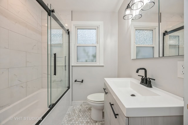 full bathroom featuring vanity, combined bath / shower with glass door, toilet, and a wealth of natural light