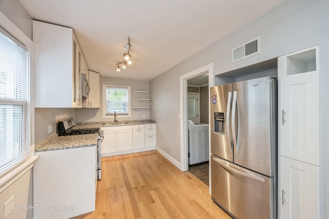 kitchen with light stone counters, white cabinets, sink, stainless steel appliances, and light wood-type flooring