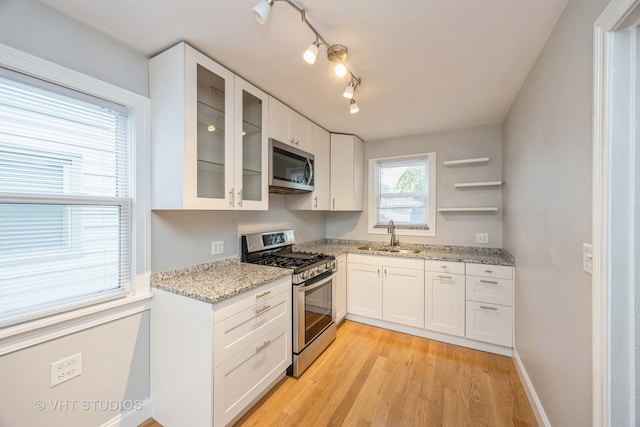 kitchen with white cabinets, sink, stainless steel appliances, and light hardwood / wood-style floors