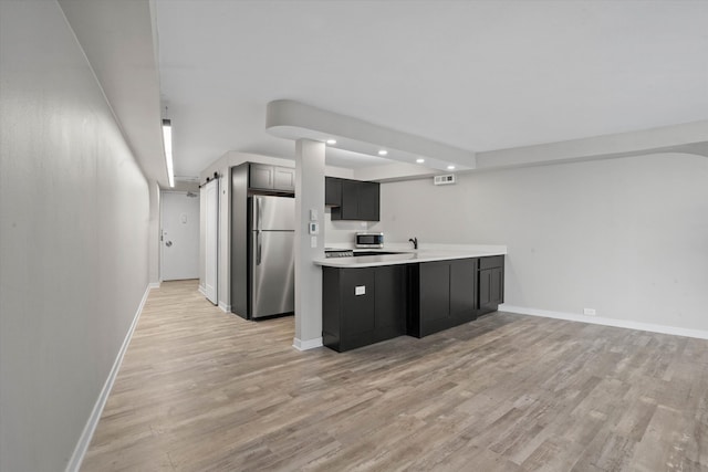 kitchen with light wood-type flooring, kitchen peninsula, and appliances with stainless steel finishes