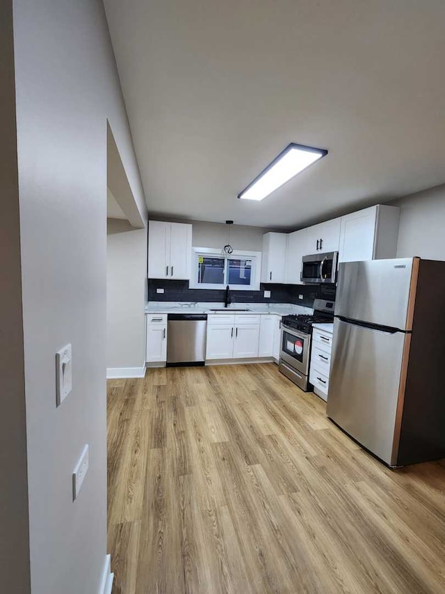 kitchen featuring stainless steel appliances, white cabinets, light wood-type flooring, and sink