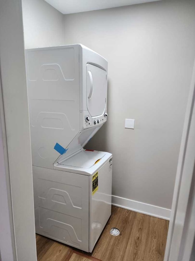 washroom featuring hardwood / wood-style flooring and stacked washer and clothes dryer