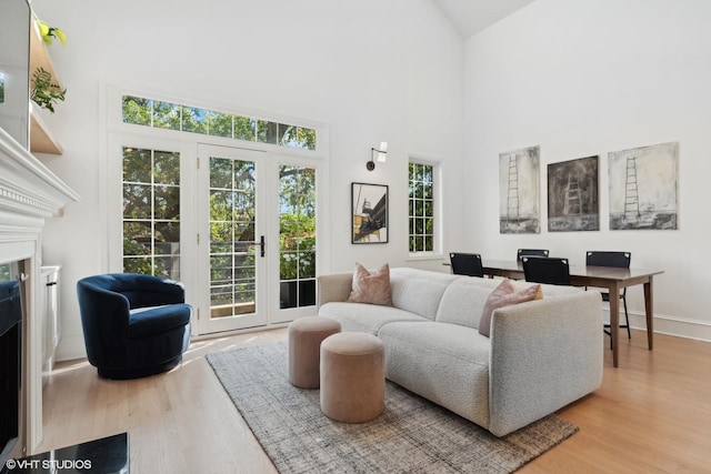 living room with high vaulted ceiling, french doors, and light wood-type flooring