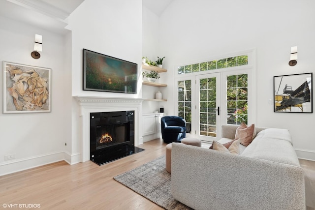 living room featuring french doors, a high ceiling, and light wood-type flooring