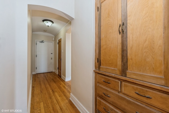 corridor with light hardwood / wood-style flooring and ornamental molding