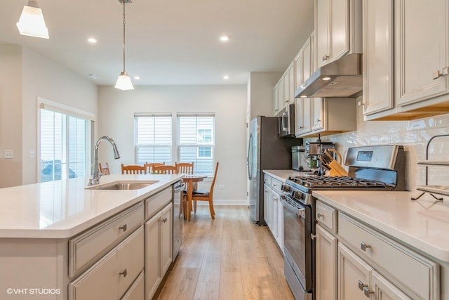 kitchen featuring sink, an island with sink, pendant lighting, stainless steel appliances, and decorative backsplash