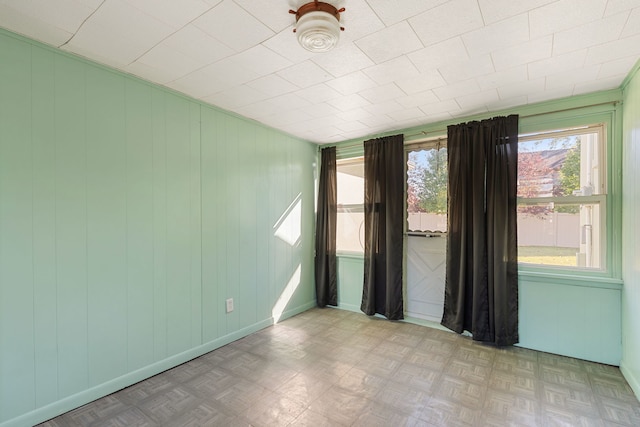 unfurnished room featuring wooden walls