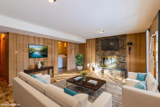 living room featuring a brick fireplace, washer / clothes dryer, and wooden walls