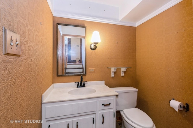 bathroom featuring toilet, ornamental molding, and vanity