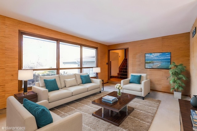 living room with a healthy amount of sunlight, wooden walls, and light colored carpet