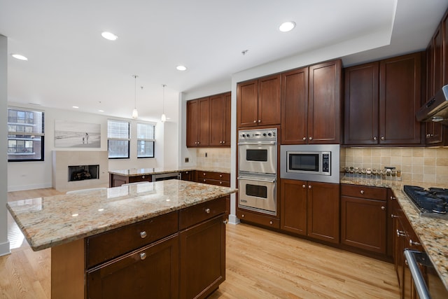 kitchen featuring pendant lighting, stainless steel appliances, light wood-type flooring, and a kitchen island