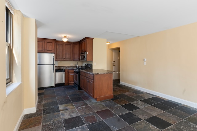 kitchen featuring appliances with stainless steel finishes, kitchen peninsula, and dark stone countertops