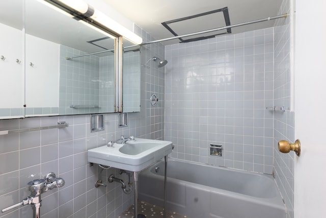 bathroom featuring tiled shower / bath, tile walls, and sink