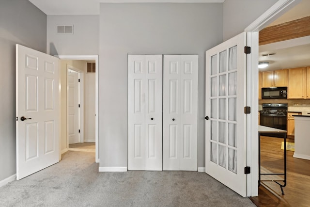 unfurnished bedroom featuring light colored carpet, a closet, and a towering ceiling