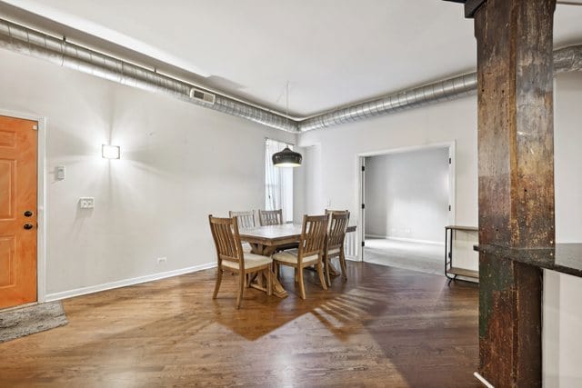 dining area with dark wood-type flooring and a wood stove