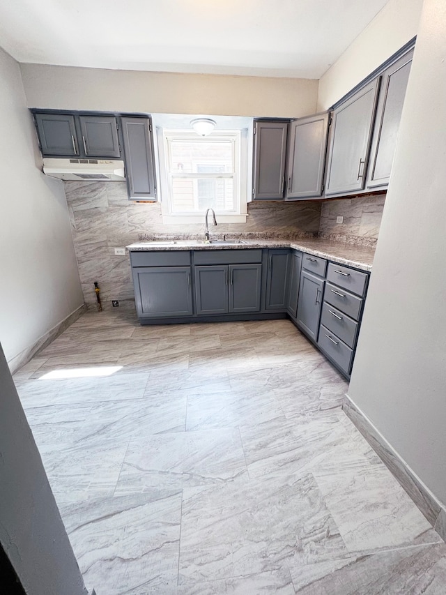 kitchen with gray cabinets, decorative backsplash, and sink