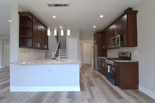 kitchen with tasteful backsplash, kitchen peninsula, hanging light fixtures, light hardwood / wood-style flooring, and appliances with stainless steel finishes