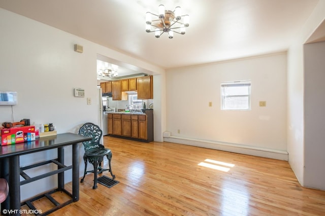 dining area featuring light wood-style flooring, an inviting chandelier, and a baseboard radiator
