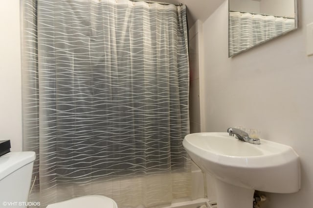 full bath with a shower with curtain, toilet, and a sink
