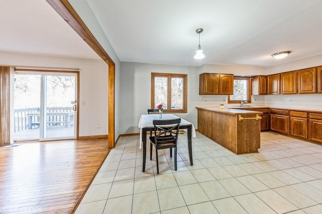 kitchen with light hardwood / wood-style floors, sink, pendant lighting, and kitchen peninsula