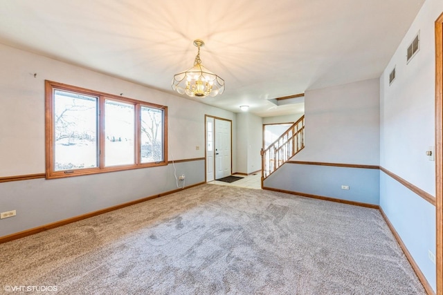 carpeted spare room with a notable chandelier