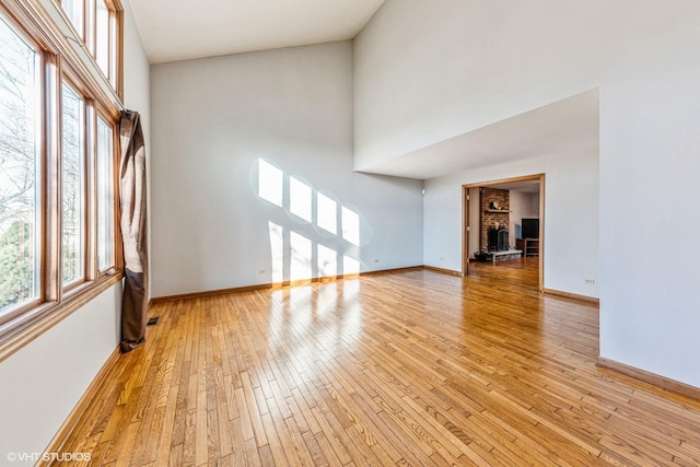 unfurnished living room featuring light hardwood / wood-style floors and a towering ceiling