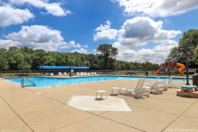 view of pool with a playground and a patio