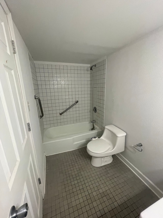 bathroom featuring tile patterned flooring, tiled shower / bath combo, and toilet