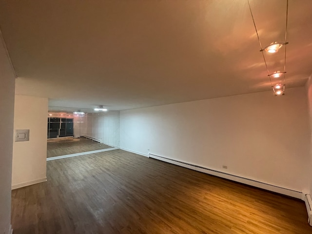 unfurnished living room with wood-type flooring, a fireplace, and a baseboard heating unit