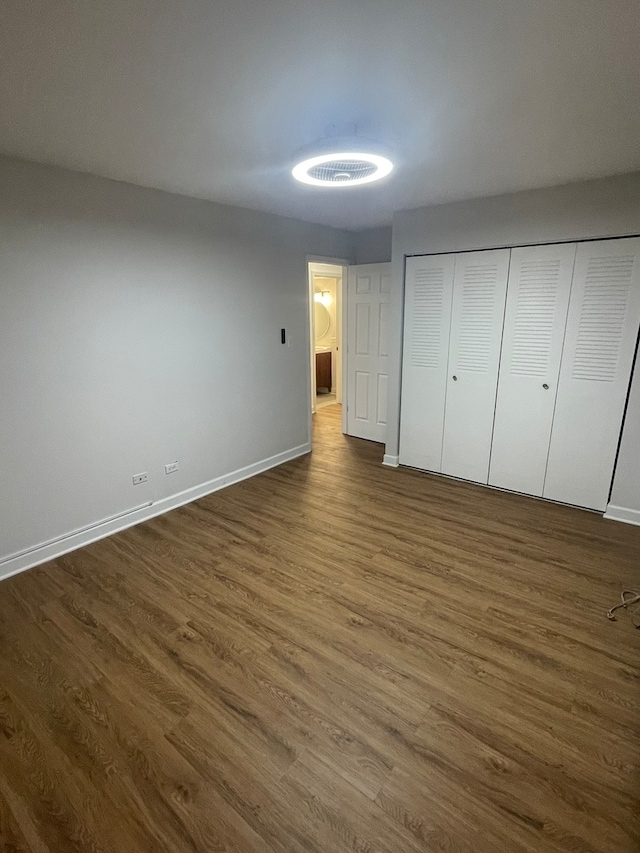 unfurnished bedroom with dark wood-type flooring and a closet