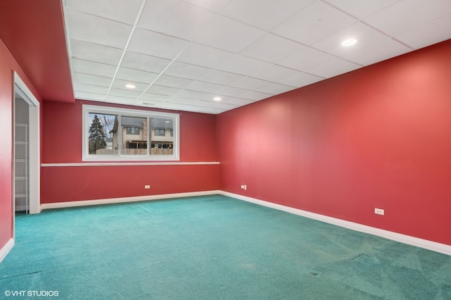 carpeted empty room featuring a drop ceiling