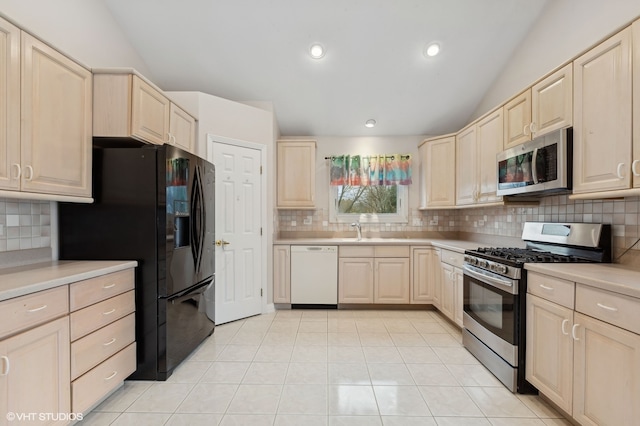 kitchen with lofted ceiling, sink, decorative backsplash, light tile patterned floors, and stainless steel appliances