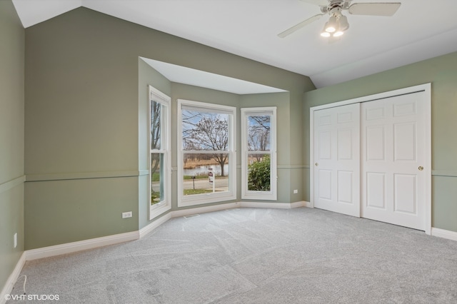 unfurnished bedroom with a closet, light colored carpet, vaulted ceiling, and ceiling fan