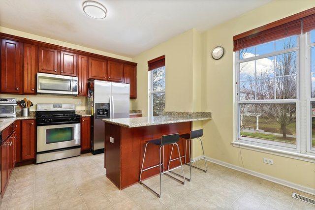 kitchen featuring kitchen peninsula, a kitchen bar, stainless steel appliances, and light stone countertops