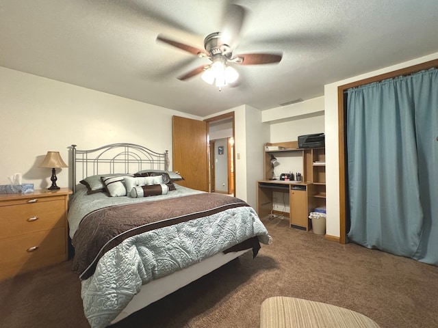 bedroom with a textured ceiling, dark colored carpet, and ceiling fan