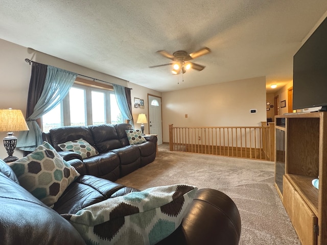 living room with ceiling fan, a textured ceiling, and carpet