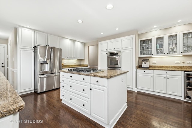 kitchen with dark wood-type flooring, white cabinetry, stainless steel appliances, and dark stone counters