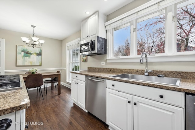 kitchen with pendant lighting, white cabinets, stainless steel appliances, sink, and a chandelier