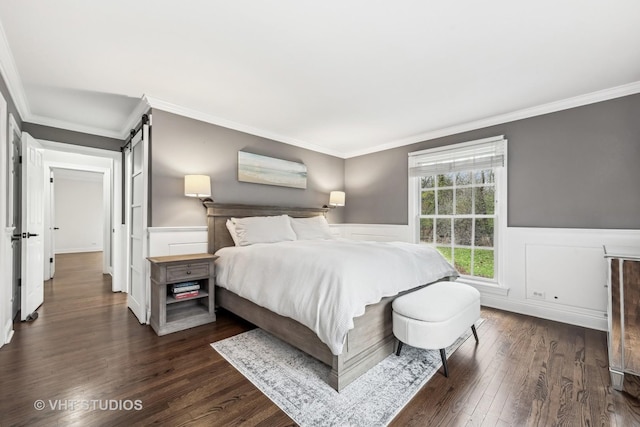 bedroom with dark hardwood / wood-style flooring, a barn door, and ornamental molding