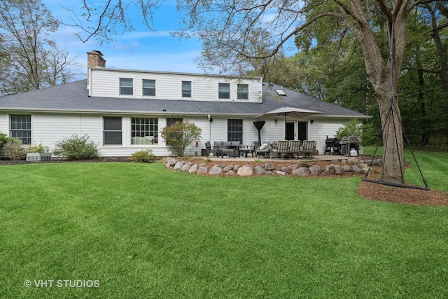 back of house with cooling unit and a lawn