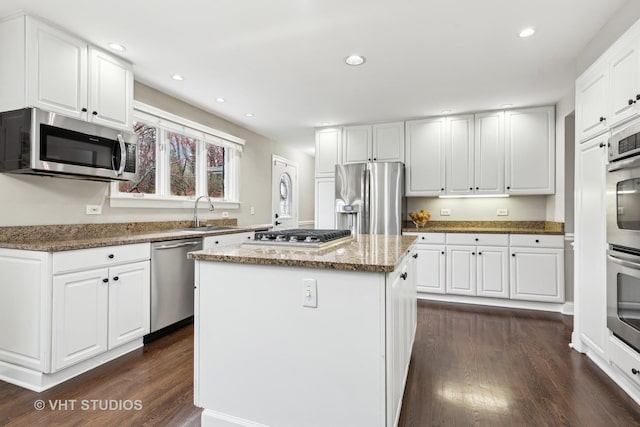 kitchen with dark hardwood / wood-style floors, a center island, white cabinetry, stainless steel appliances, and light stone counters