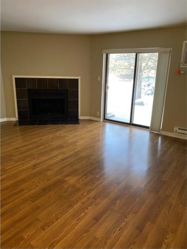 unfurnished living room featuring dark hardwood / wood-style floors and a tile fireplace