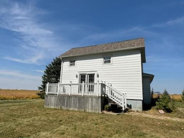 back of property with a deck and a lawn