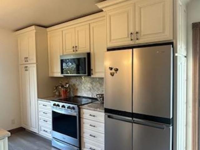 kitchen with stainless steel appliances, decorative backsplash, and white cabinets