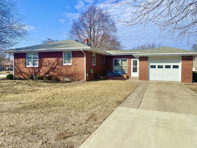 view of front of house featuring an attached garage, brick siding, concrete driveway, a front lawn, and a chimney