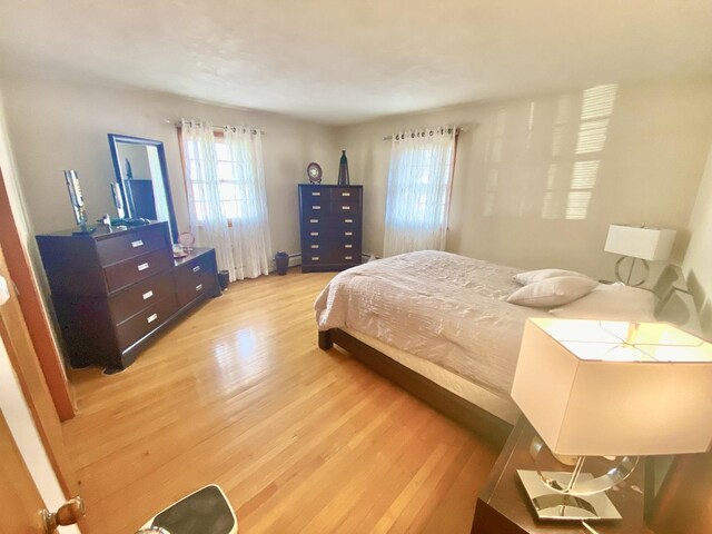 bedroom with hardwood / wood-style floors and a baseboard radiator