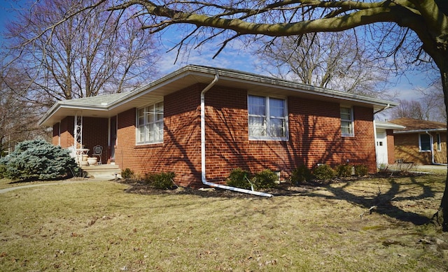 view of side of home with brick siding, a yard, and an attached garage