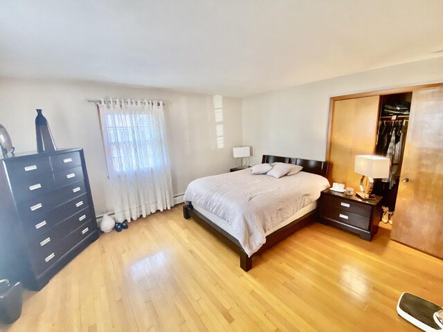 bathroom with tile walls, vanity, hardwood / wood-style floors, toilet, and a baseboard heating unit